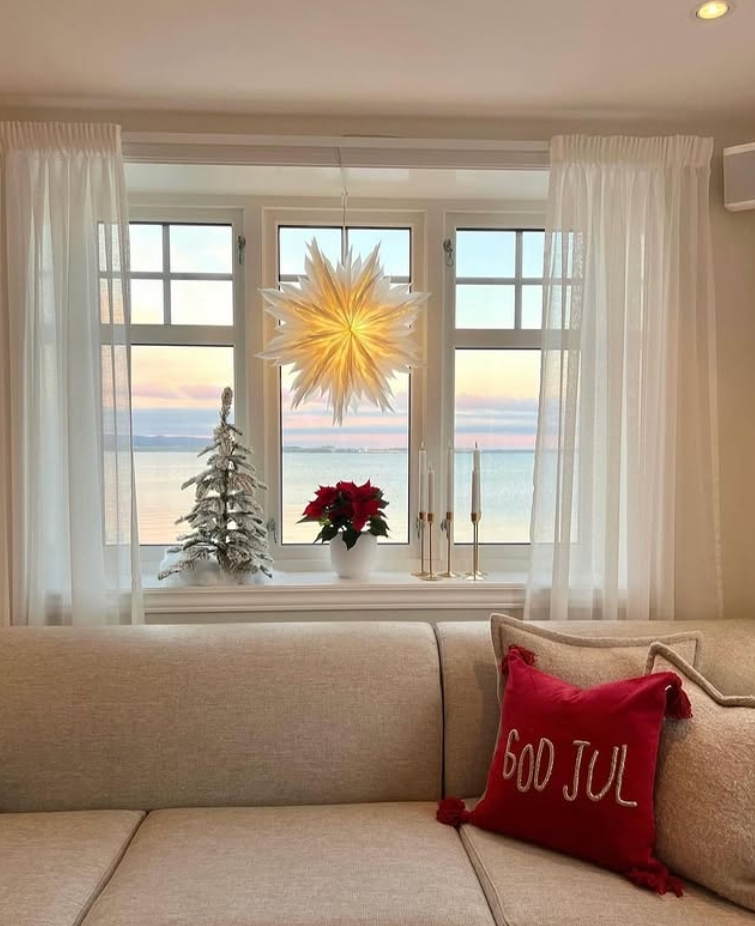 Klassisk hvitmalt sidehengslet vindu i stue med utsikt mot havet.